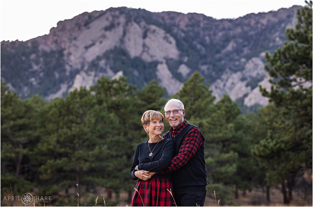 Sweet photo of grandparents laughing together with a gorgeous mountain view behind them at Shanahan Ridge Trailhead in Boulder