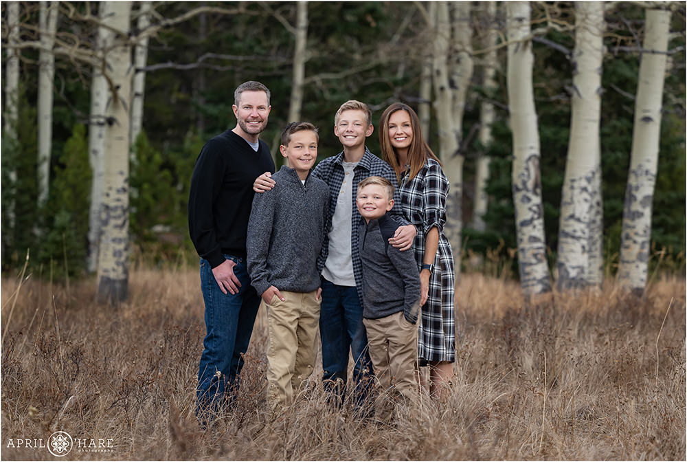 A beautiful family of 5 wearing gray, black, and khaki at their mountain meadow family portrait session in Colorado