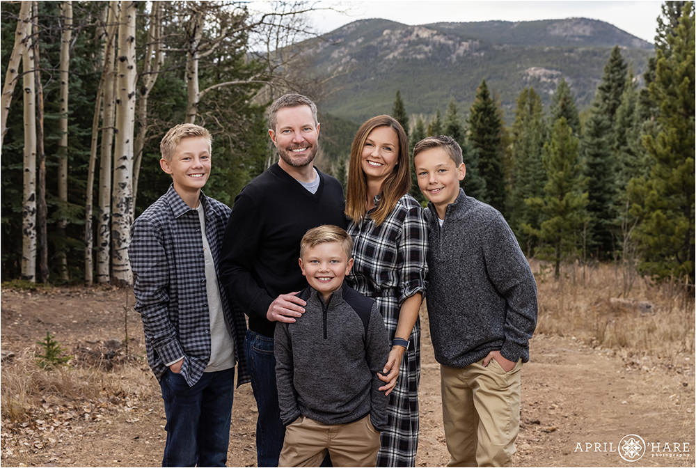 A family of five wearing black, white, and gray with a mountain backdrop in Evergreen Colorado
