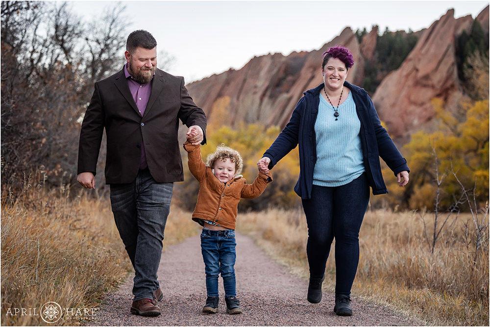 A family of three walk down the path at Roxborough State Park in Littleton Colorado