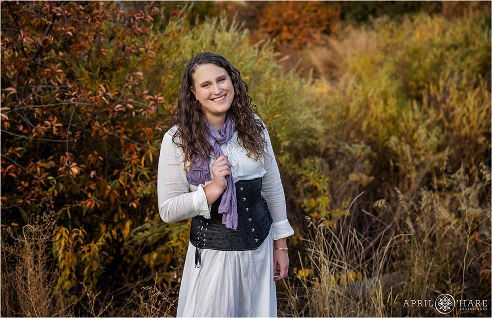 Beautiful fall color portrait for a curly haired woman wearing a flowy white dress, lavendar scarf, and a black corset in Denver Colorado