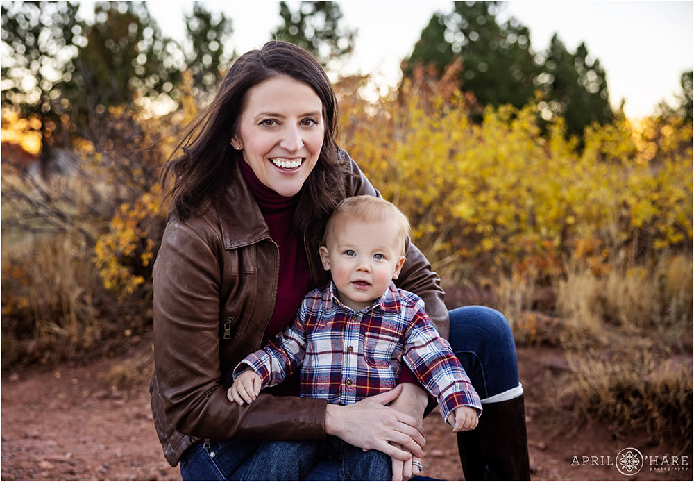 Fall color backdrop for a portrait of a young mom with his sweet baby boy who is wearing a plaid long sleeved shirt in Boulder