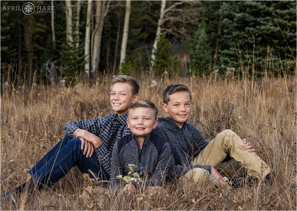 3 brothers sit in a mountain meadow in Evergreen Colorado