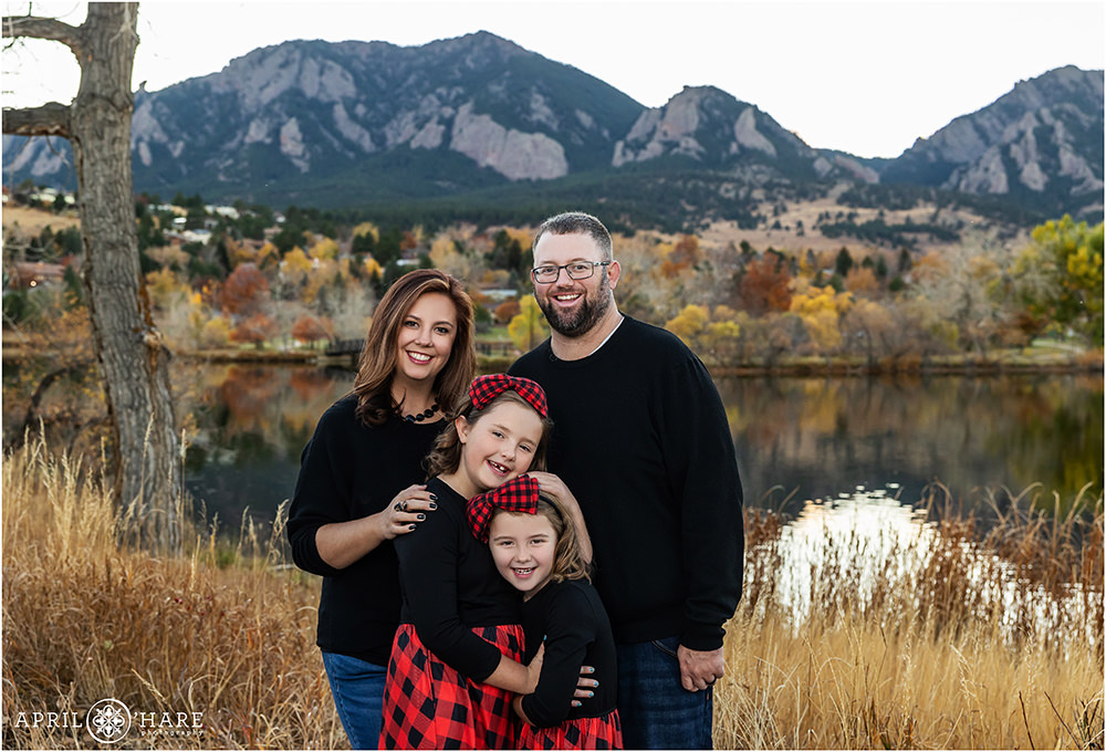 A family of four with two daughters with a pretty fall backdrop at Viele Lake in Boulder