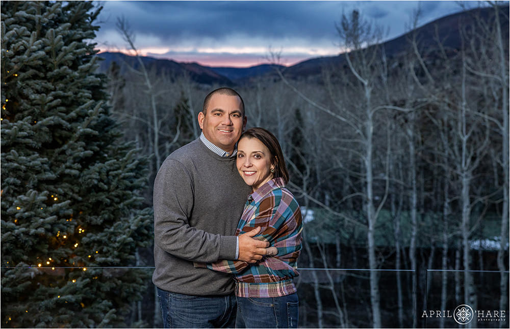 Parents celebrating their wedding anniversary get a portrait on a balcony with mountain views in the backdrop in Aspen Colorado