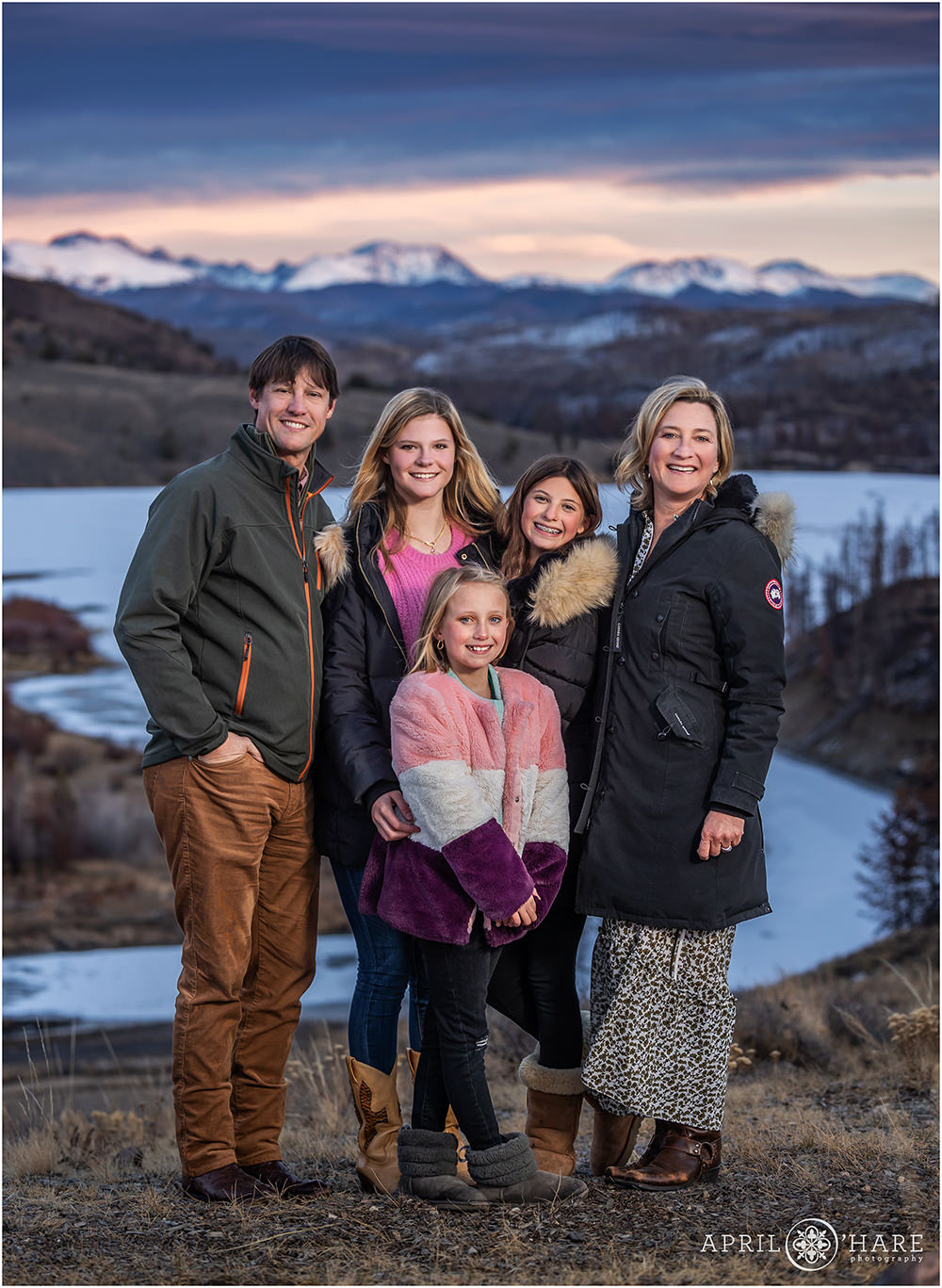 Family of 5 stand in front of a pretty sunset mountain backdrop in Granby Colorado