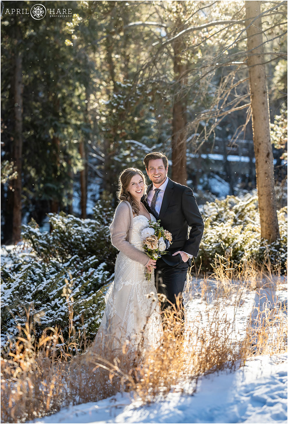 Wedding couple pose in a pretty mountain forest in the snow in Keystone Colorado