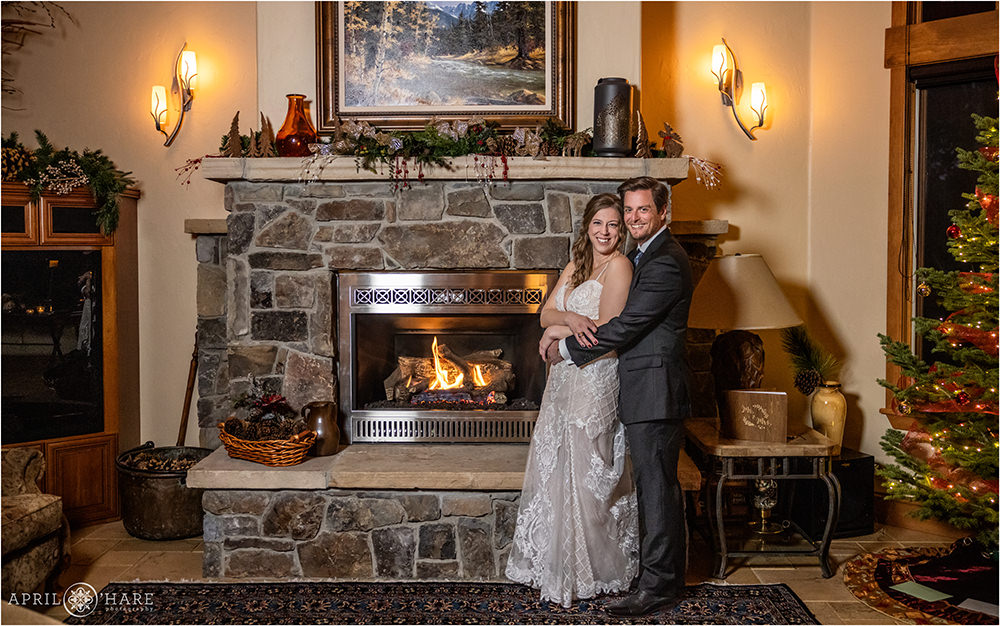 Cute wedding couple snuggle in front of the fireplace on their wedding day during winter in Keystone Colorado