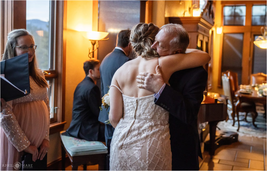 Bride hugs her dad after he walks her down the aisle at her indoor wedding ceremony in Keystone Colorado