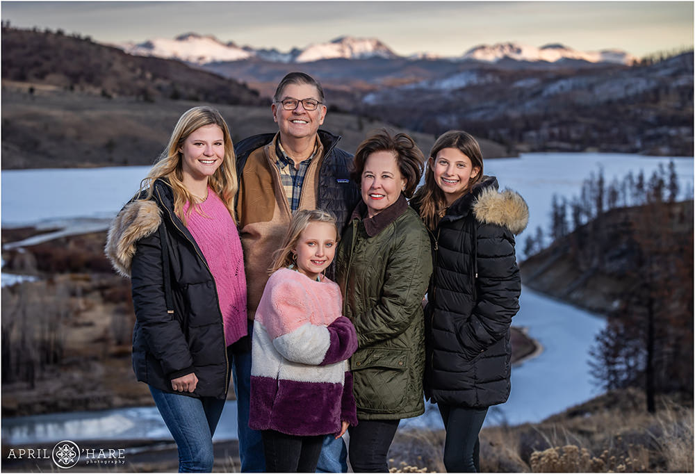 Grandparents pose with their grandkids in front of a pretty sunset mountain backdrop at C Lazy U Ranch