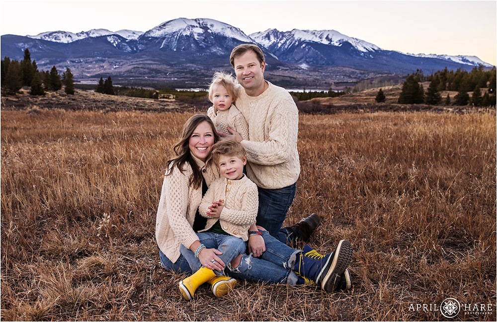 A family of 4 wearing cream sweaters in Summit County with Buffalo Mountain backdrop in Colorado