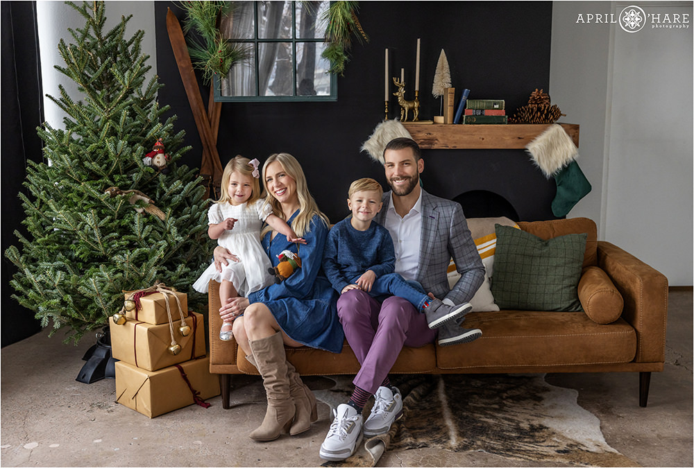 Cute photo of a family of four with two young kids at a styled Christmas setting at an indoor Photo studio