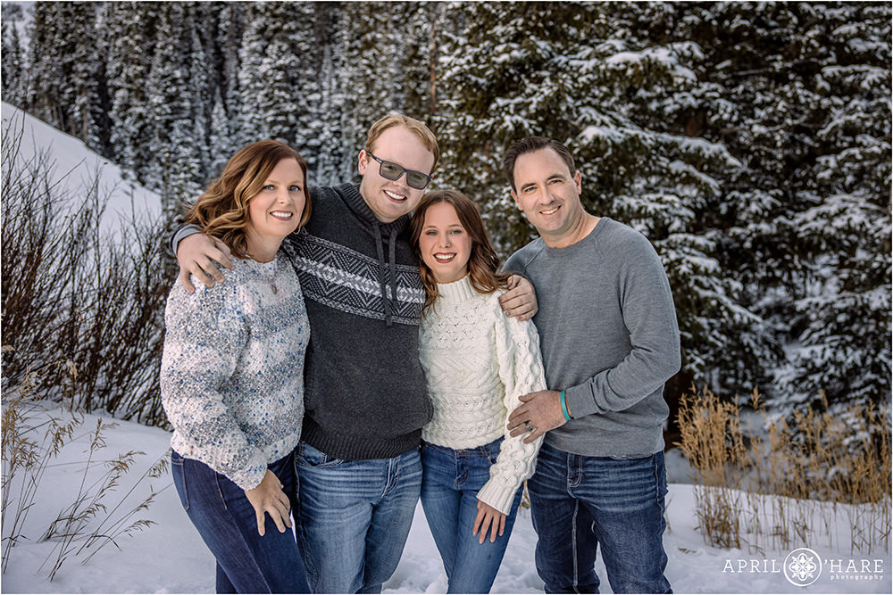 Family of four pose with pretty snowy forest backdrop at Berthoud Pass near Winter Park Colorado
