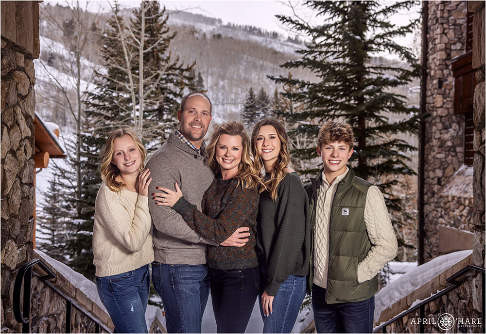 A beautiful family of 5 pose together with a nice mountain backdrop and evergreen trees behind them at Beaver Creek Ski Resort in Colorado