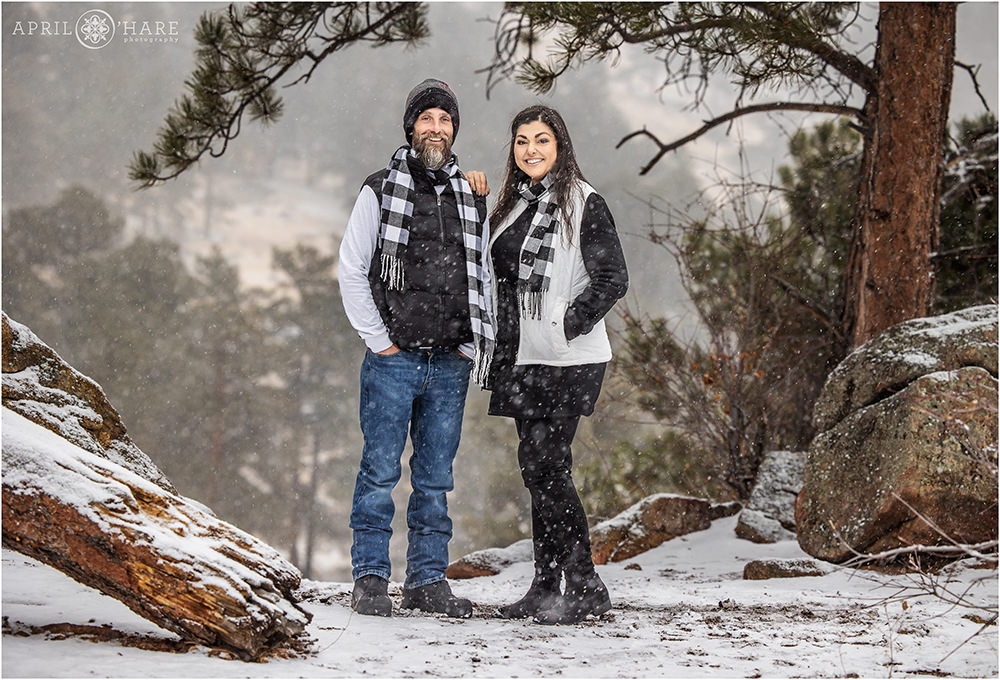 Adult siblings pose for a cute photo together during a winter storm at Rocky Mountain National Park in Colorado