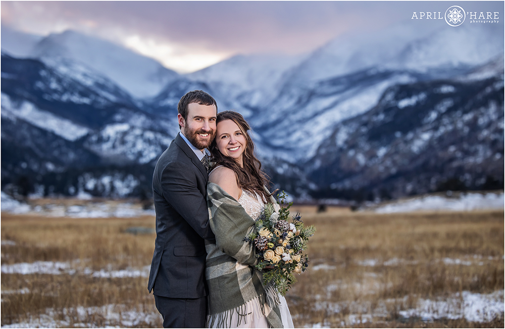 Pretty pink and purple sunset wedding portrait with mountain backdrop inside Rocky Mountain National Park in Colorado