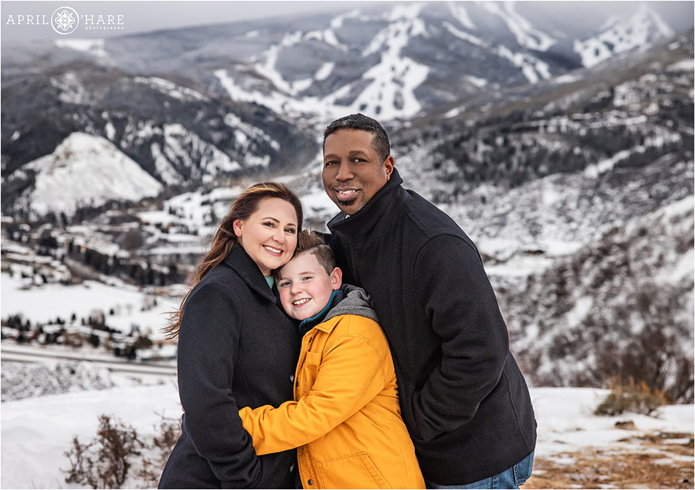 Cute family of three pose in front of a mountain ski resort in Beaver Creek Colorado