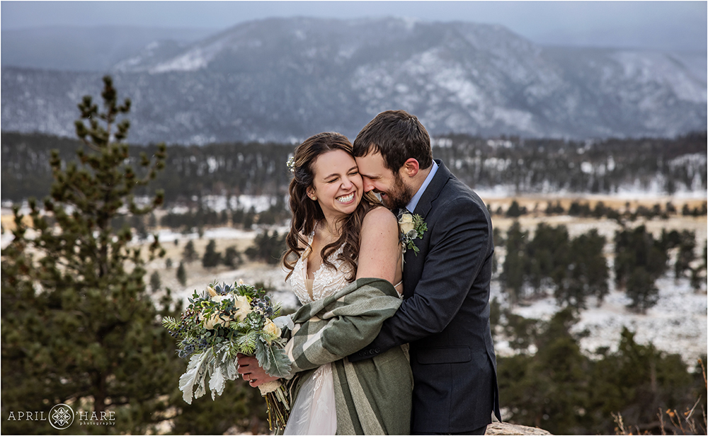 Snuggly wedding photo of a cute couple in front of a snowy tree mountain backdrop in Rocky Mountain National Park in Colorado