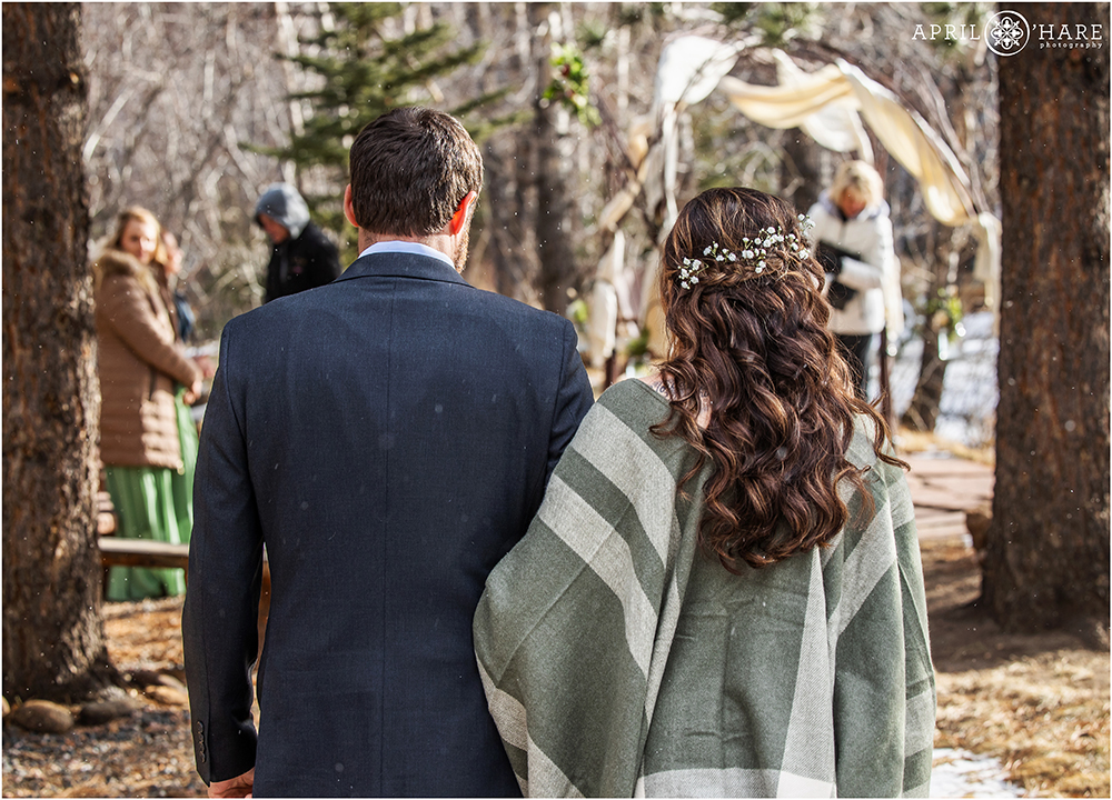 Couple walk to their outdoor wedding ceremony in front of a river in Estes Park Colorado