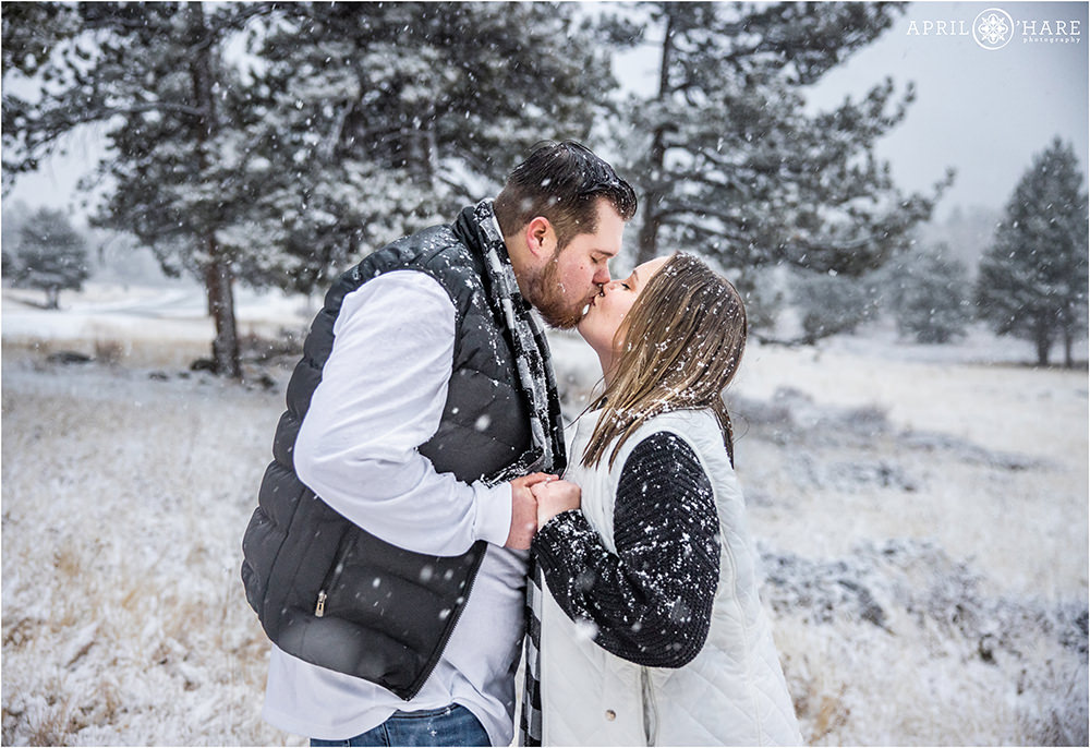Couple kisses in a winter snowstorm inside Rocky Mountain National Park in Estes Park Colorado