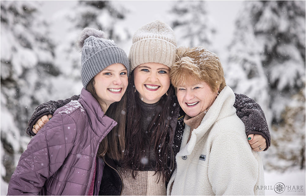 A mom with her two daughters pose for a portrait together at their winter blizzard snowstorm family photoshoot in Colorado
