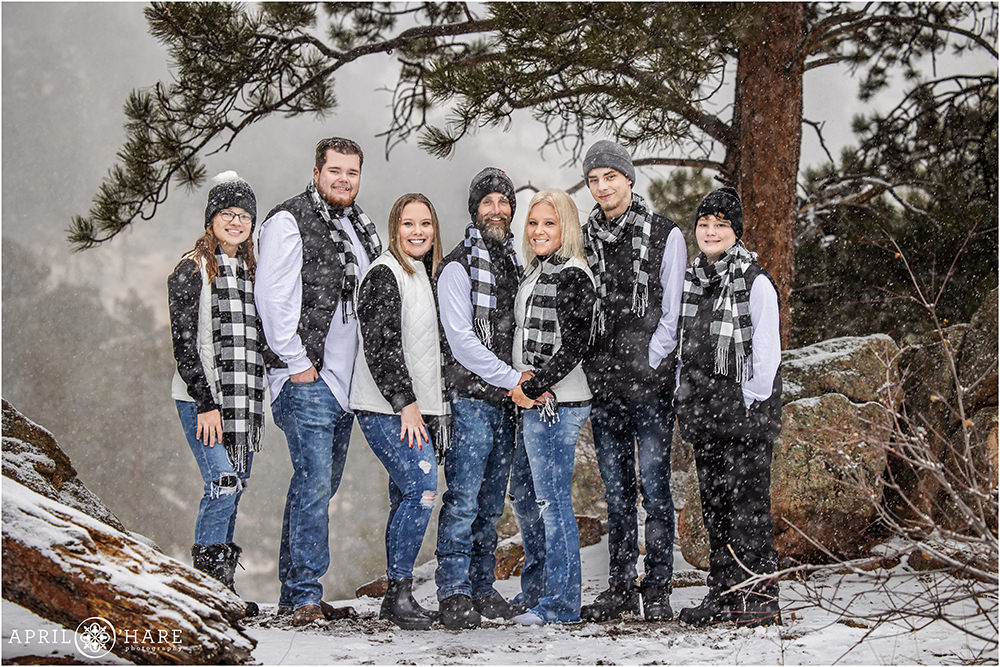 Beautiful full length portrait of a family posing for photos under a tree during a winter snowstorm in Estes Park Colorado