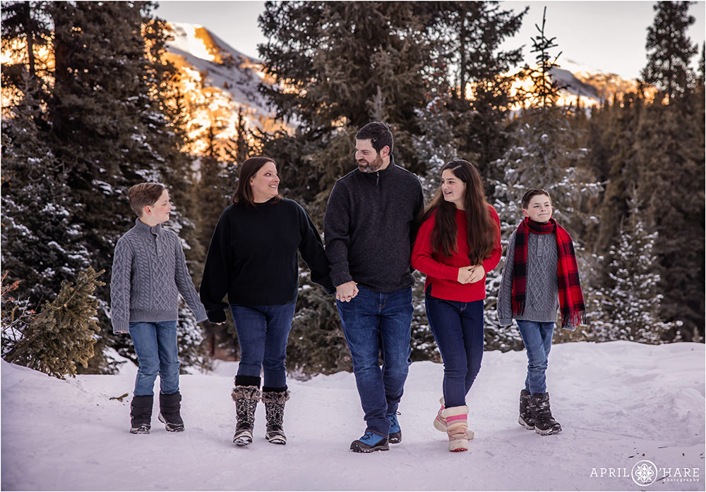 Family of 5 walk along a forest path together with a pretty mountain backdrop at Mayflower Gulch Trail
