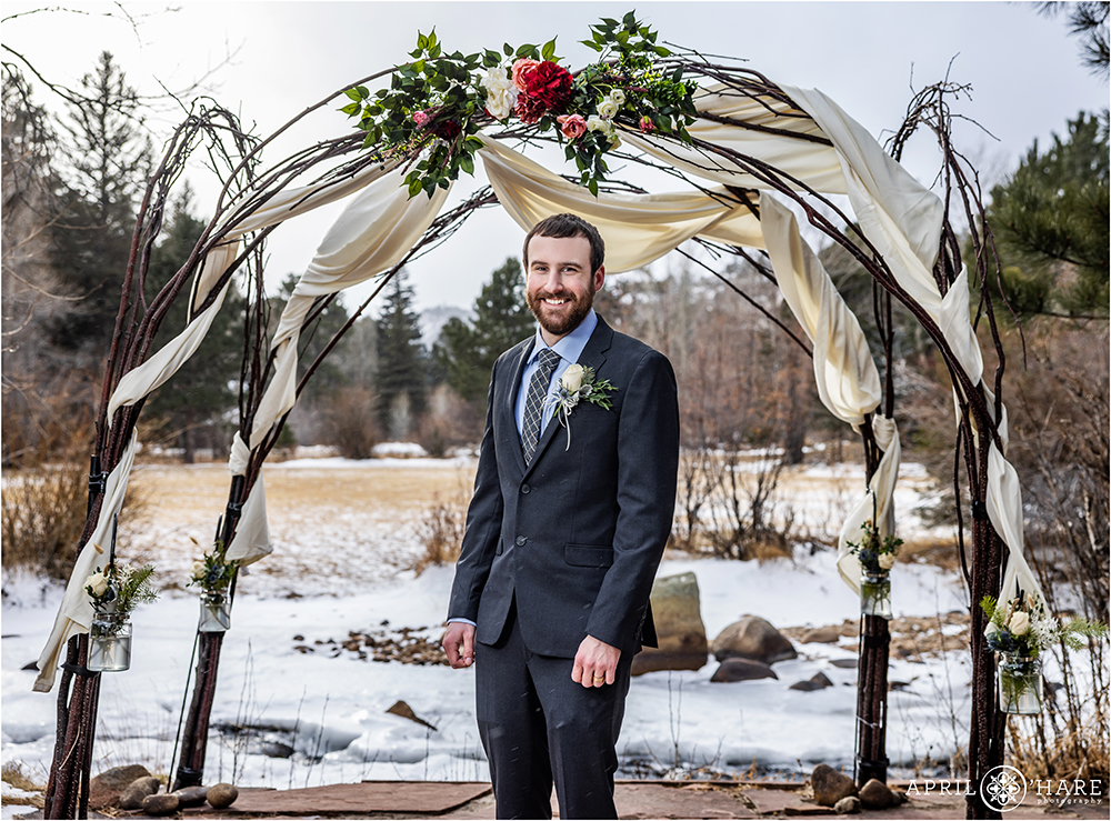 Groom portrait in front of an icy river at Romantic Riversong Inn in Estes Park Colorado