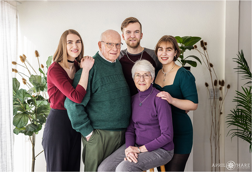 Adult grandchildren pose with their grandparents in a natural light photo studio in Longmont Colorado