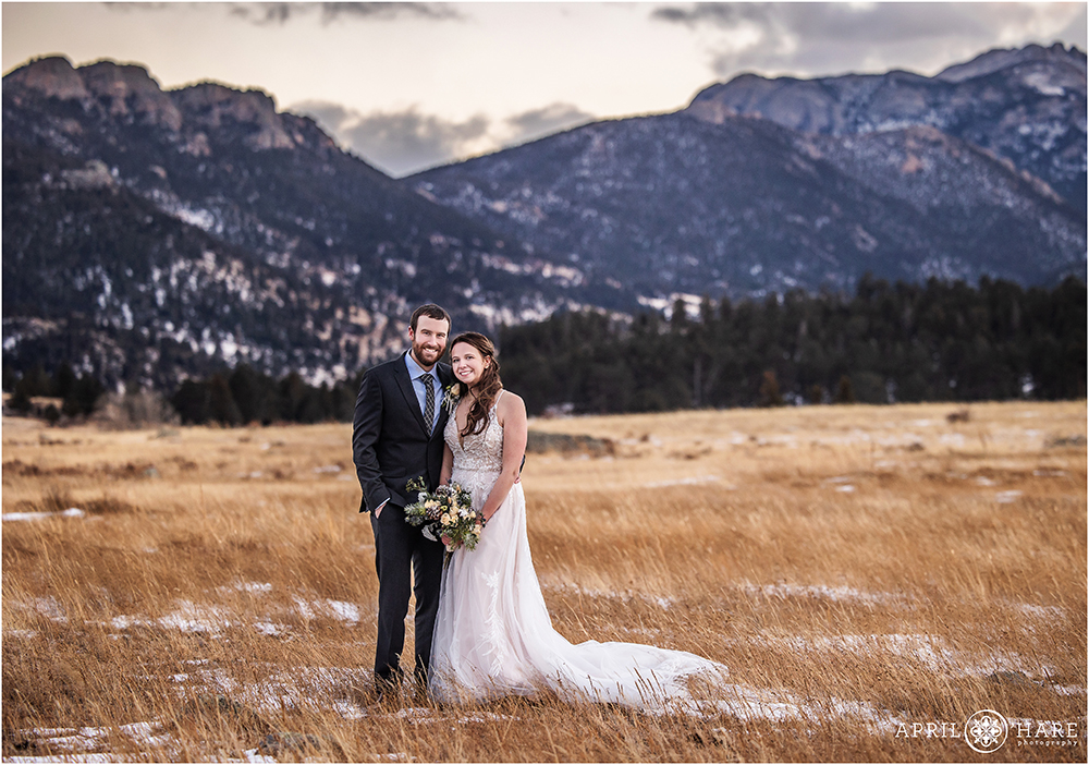 Beautiful classic wedding portrait on a freezing cold winter day in the meadow at Moraine Park with a blue mountain backdrop at Rocky Mountain National Park