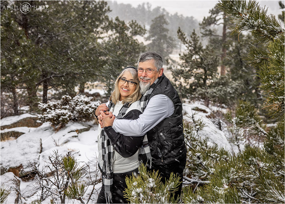 Couple posing in the evergreen tree covered in snow in Rocky Mountain National Park in Estes Park