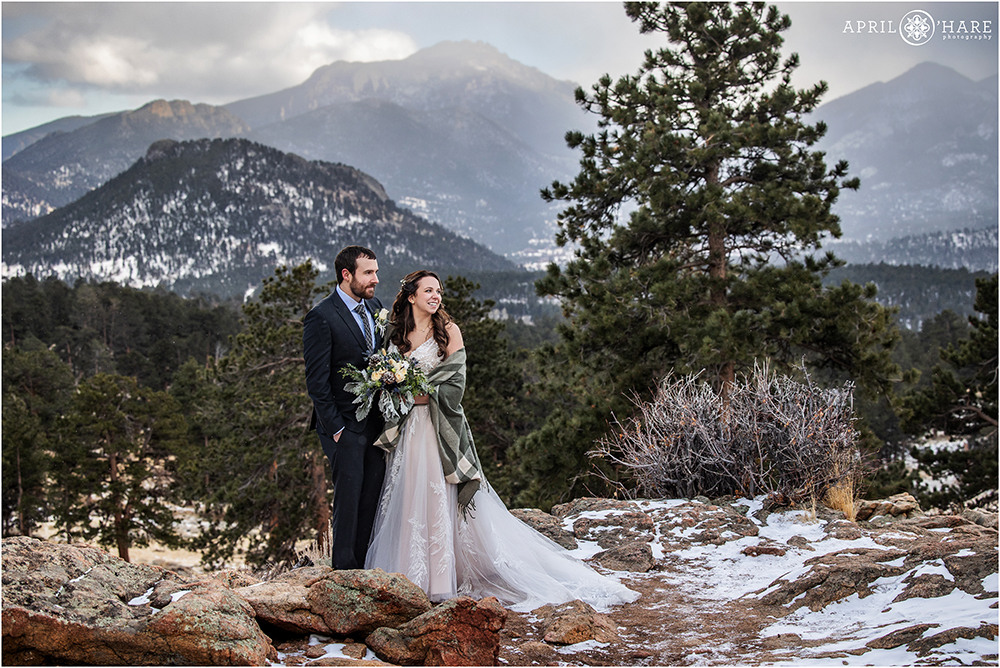 Couple look out at the mountain views together at their winter wedding portrait session inside Rocky Mountain National Park in Colorado