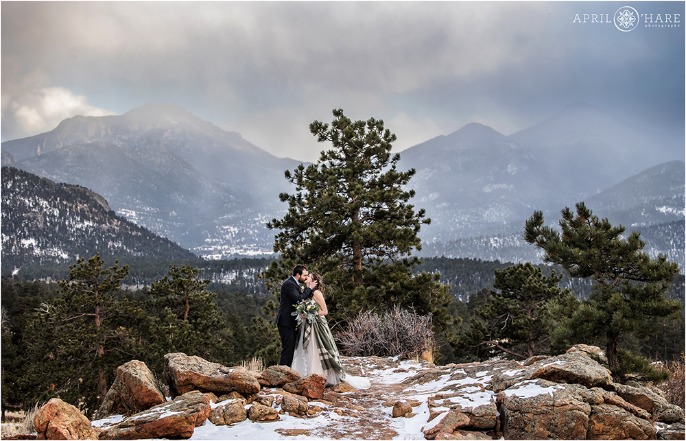 Romantic kissing photo on a winter wedding day with beautiful dramatic mountain backdrop at Rocky Mountain National Park