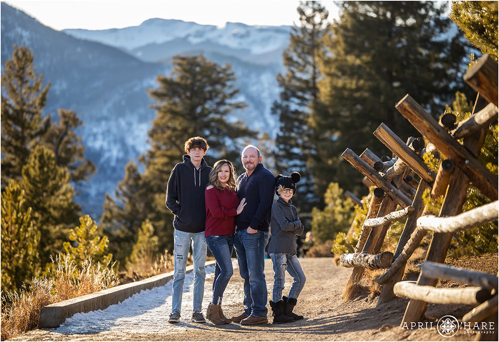 Family of four pose together on the dirt path at Sapphire Point with a huge mountain backdrop behind them