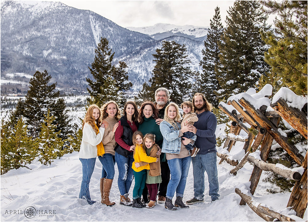 Beautiful family portrait next to rustic wood fence with a pretty snowy mountain backdrop in Colorado