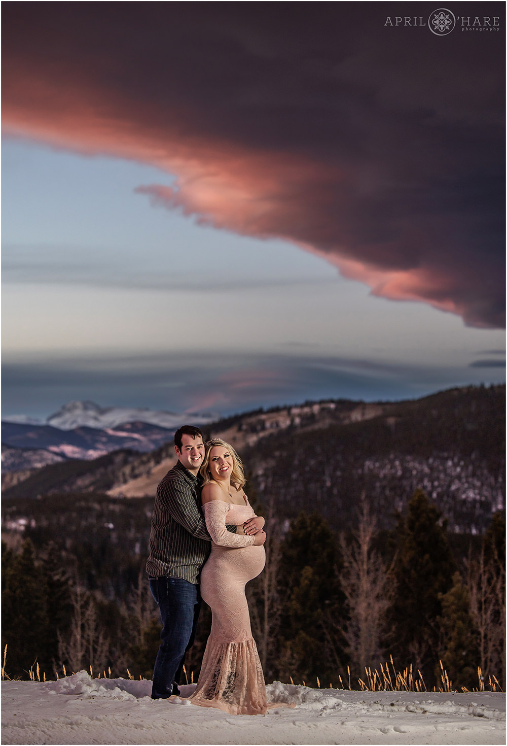Colorado maternity session with a pretty mountain backdrop in the snow with gorgeous purple and pink sunset in Evergreen CO