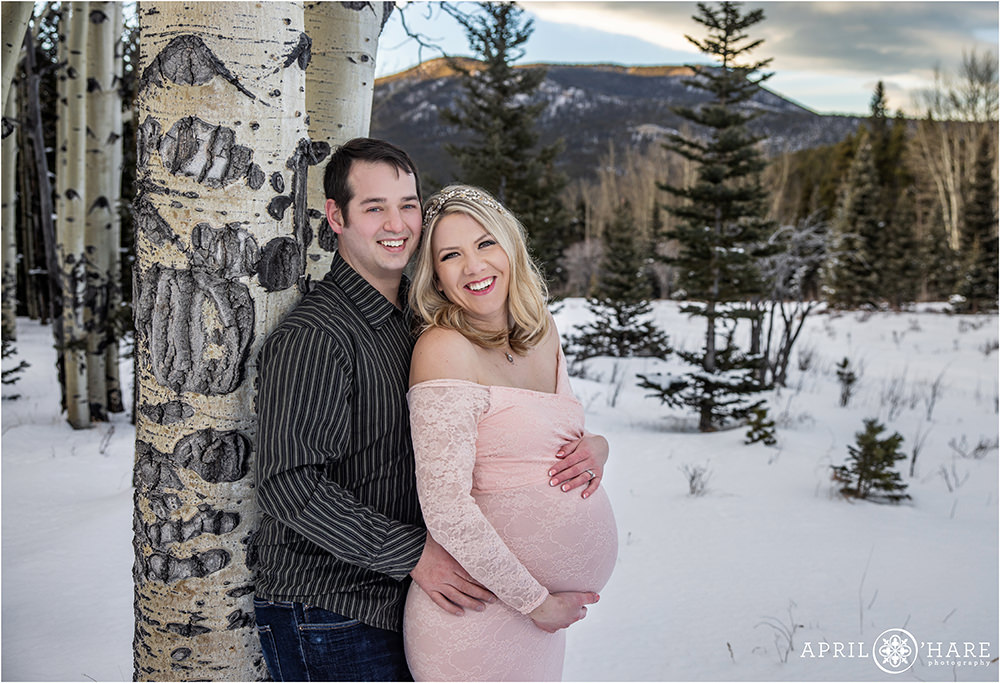 Beautiful snowy maternity portraits with mountain backdrop and aspen tree forest in Colorado