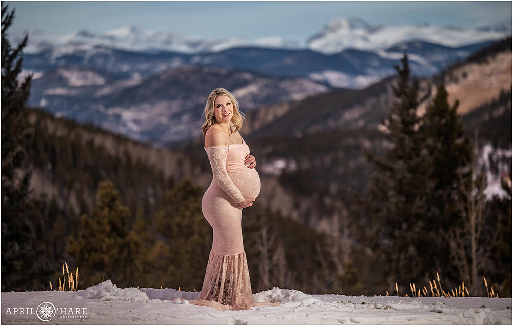 Expecting mother poses for a pretty sunset maternity portrait with mountain backdrop in Evergreen Colorado