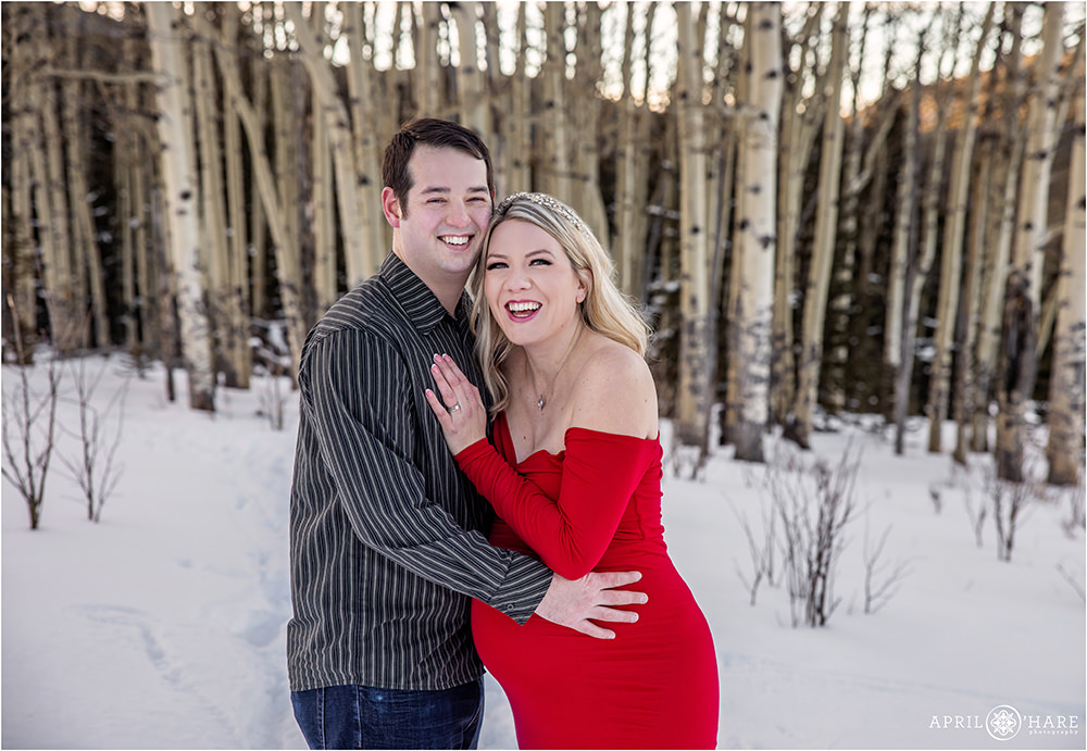 Cute couple expecting their first baby laugh together in an aspen tree forest in Evergreen Colorado