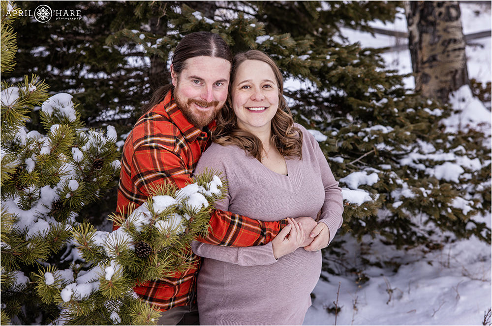 Sweet portrait of an expecting couple in a winter forest setting in Colorado for their maternity session