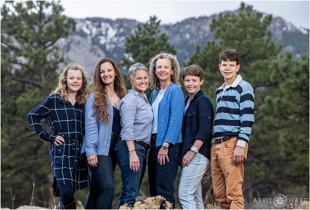 Family wearing shades of blue in front of a pretty mountain backdrop during spring in Colorado