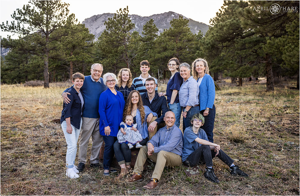 Extended family wearing blue pose in the woods of Boulder CO