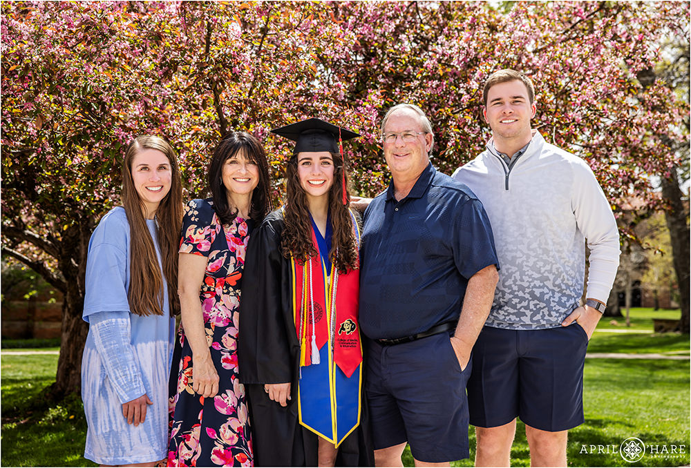 Family portrait in front of a pretty tree blossom backdrop during spring after a graduation at CU Boulder