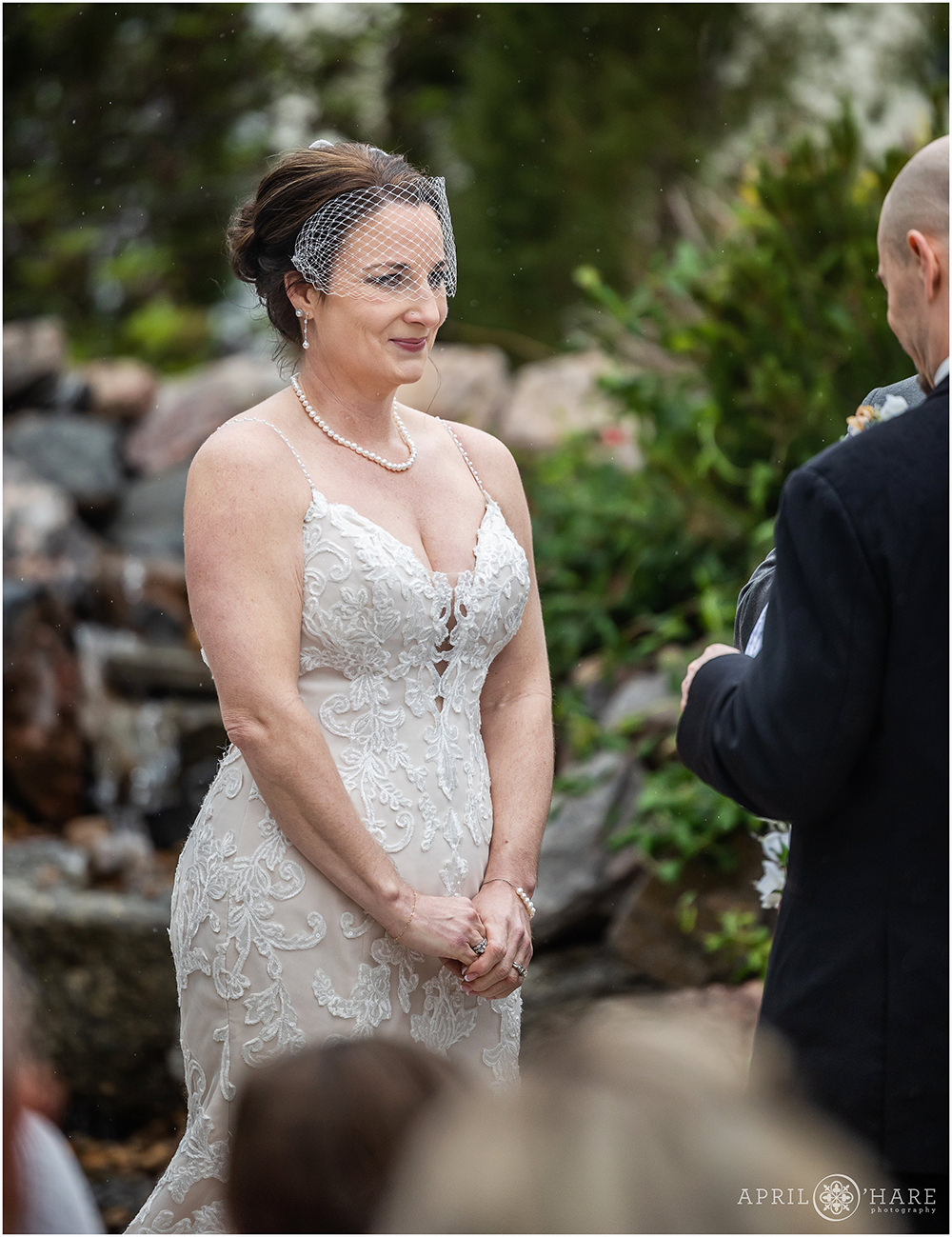 Married woman looks at her husband as he renews his vows in a pretty garden in Littleton Colorado