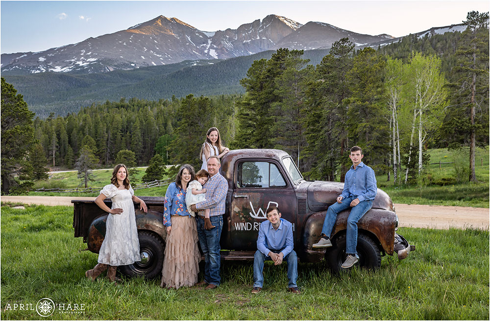 A family with 5 kids pose next to a cool old vintage pick up parked in front of Longs Peak mountain view in Estes Park