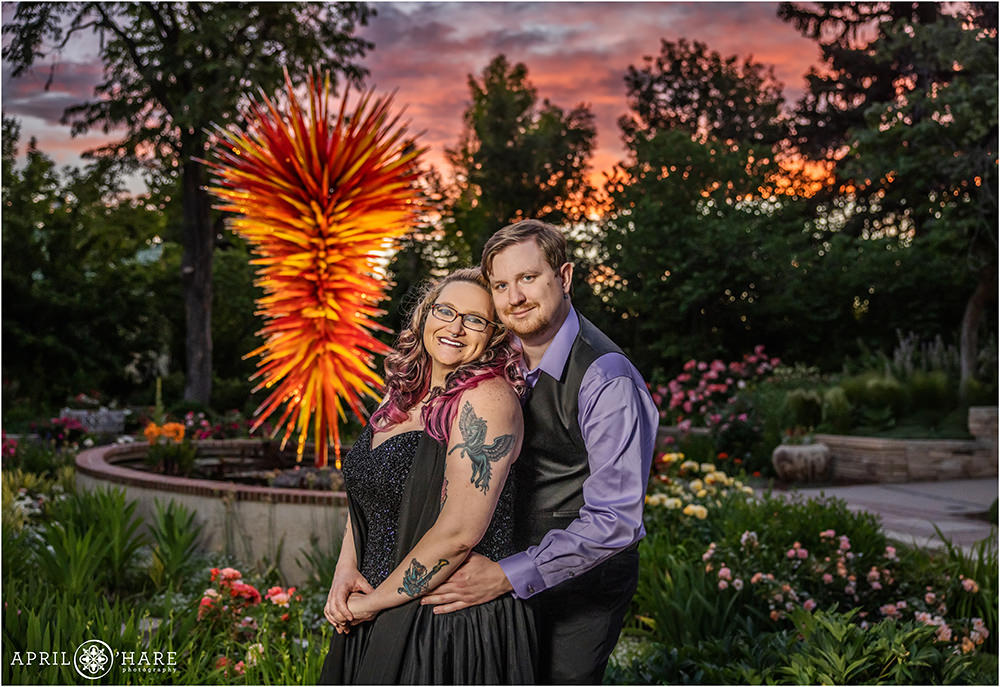 Pretty pink and orange sunset engagement photo with the Denver Botanic Gardens Chihuly sculpture in the backdrop