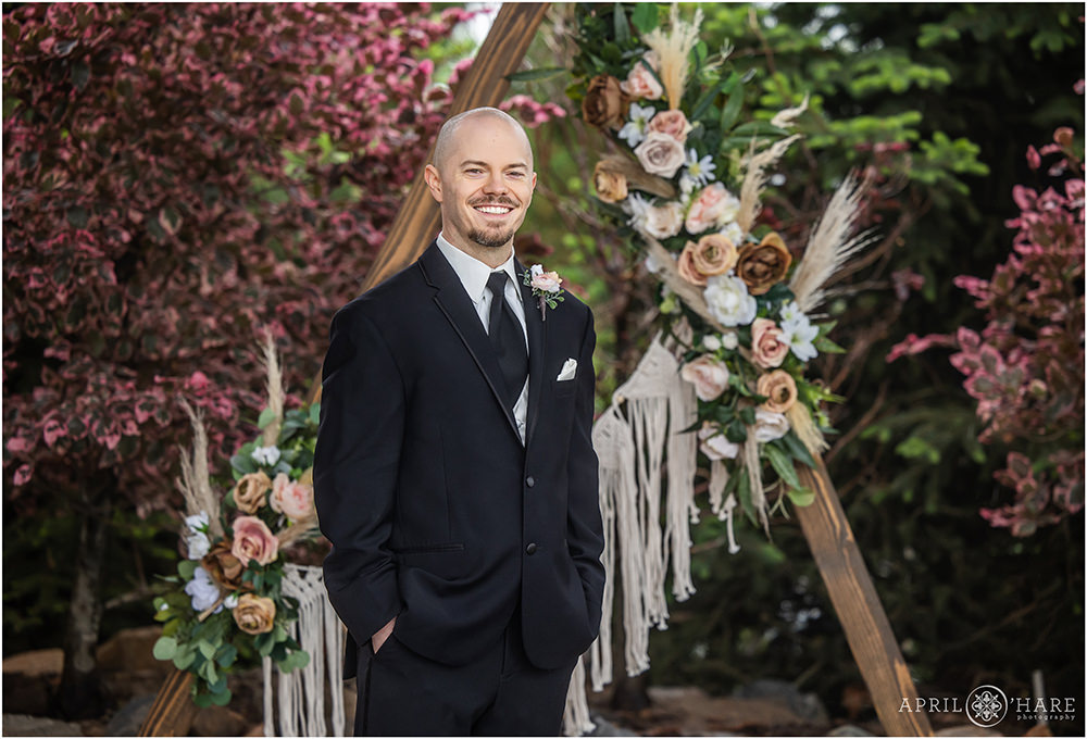 Classic portrait of a groom with a boho designed backdrop with faux silk flowers at his vow renewal party