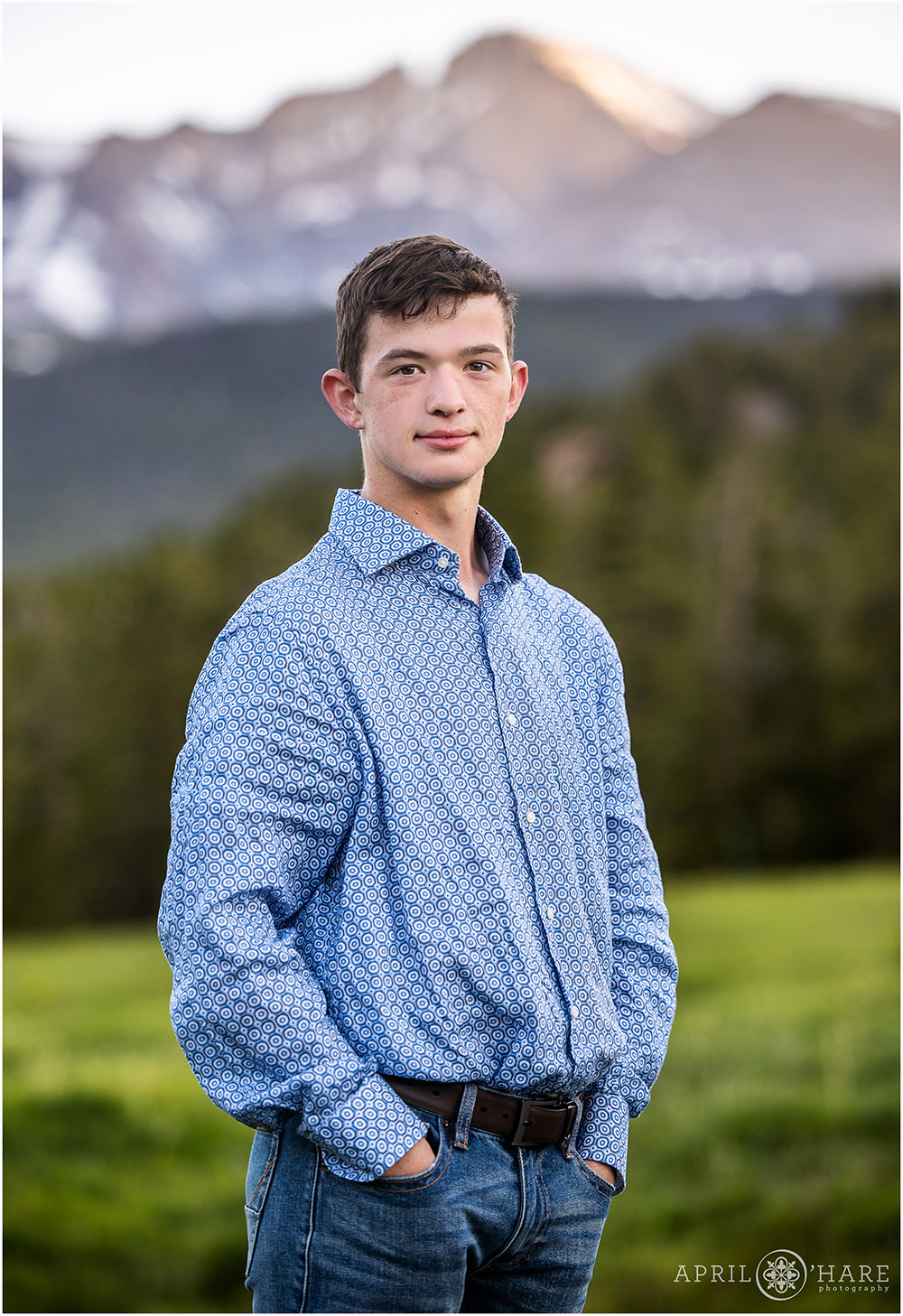 Classic senior photo for a young man standing in front of Longs Peak mountain view in Colorado