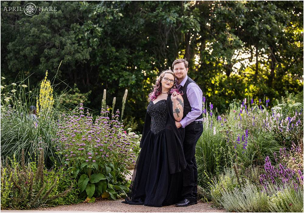 Couple wearing black and purple stands on a path surrounded by pretty purple plants at Denver Botanic Gardens in Colorado