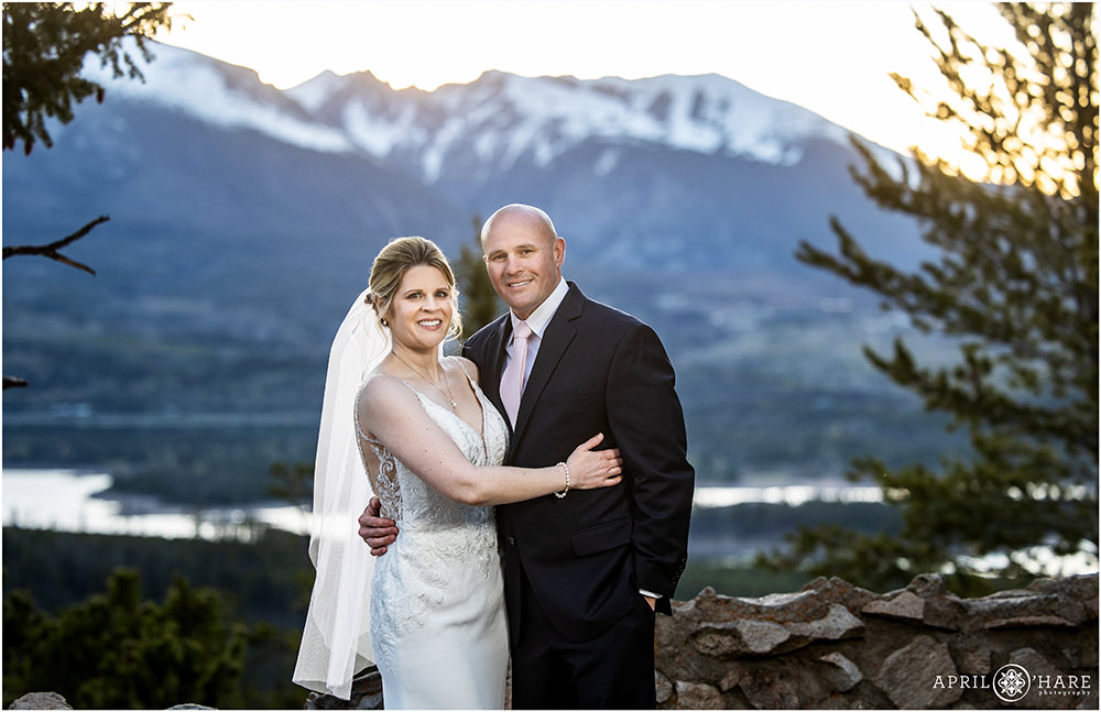 Bride and groom pose for a pretty portrait with a mountain backdrop at sunset at Sapphire Point